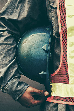 Construction worker holding hard-hat under arm